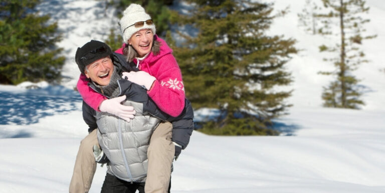 Elderly Couple Playing in the Snow Together During a Winter Day at a Senior Living Community
