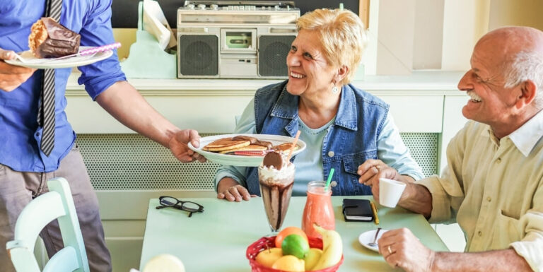 Staff Member Serving Retro Diner-Style Breakfast at Memory Care Facility